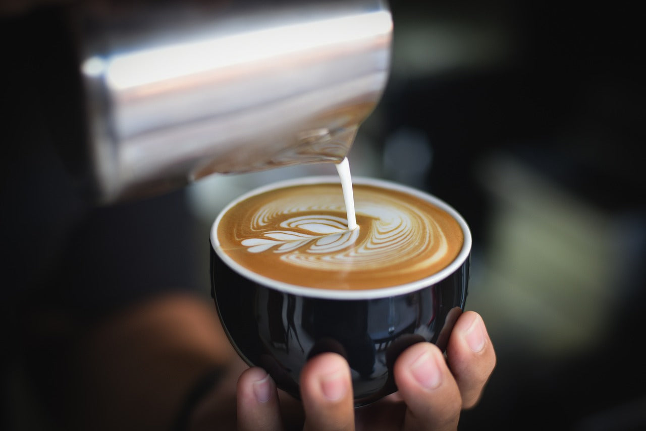 Pouring steamed milk into espresso coffee